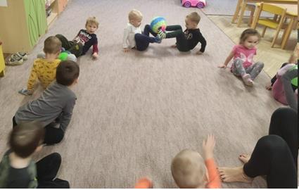dzieci ćwiczą z piłką na dywanie