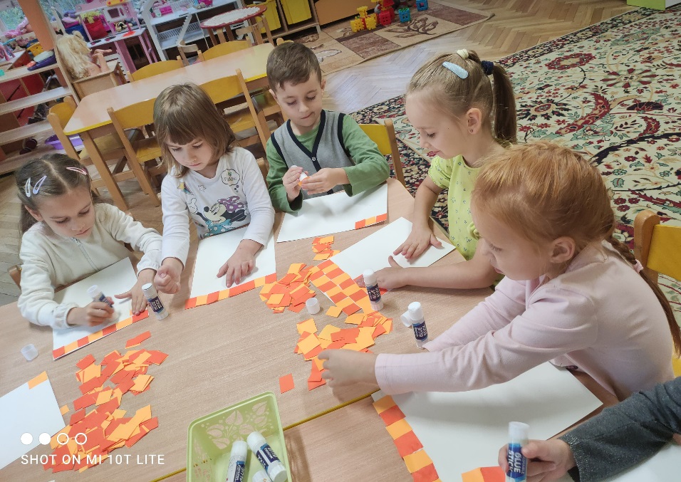 Dzieci naklejają kolorowe kawałki papieru na karton