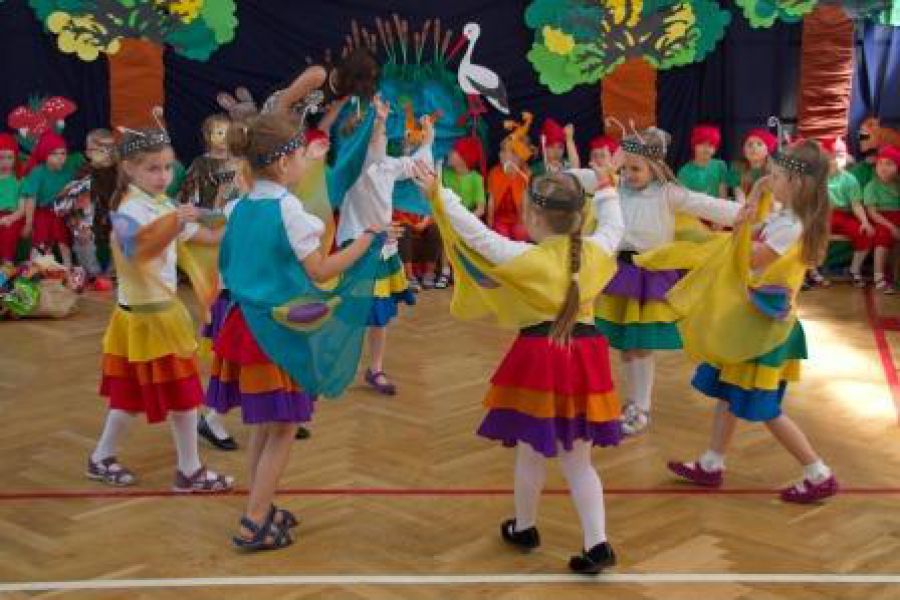 dzieci w kolorowych strojach tańczą w kole
