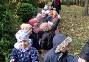 Dzieci w okryciach wierzchnich idą parami z nauczycielkami do autokaru.