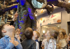 Grupa dzieci ogląda w korytarzu teatru dekoracje teatralne.