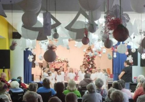 Dzieci w strojach aniołków występują na scenie przed seniorami z DPS.