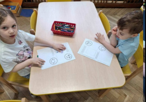 dwoje dzieci przy stoliku rysuje emocje