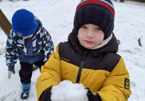 chłopiec trzyma kulę ze śniegu