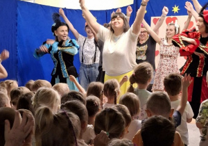 grupa mam na scenie w przebraniach odgrywają dladzieci bajkę, a dzieci na widowni oglądają