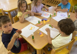 dzieci wyklejają balonik kawałkami papieru przy stoliku