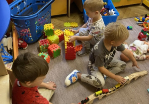 dzieci bawią się na dywanie klockami i samochodzikami