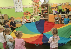 Dzieci tańczą stojąc wokół chusty animacyjnej.