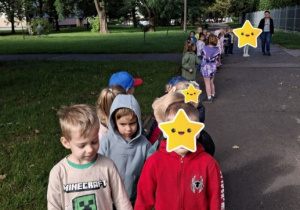 Dzieci idą parami alejką osiedla