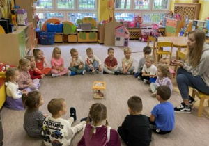 dzieci siedzą w kole i słuchają opowiadania hodowcy zwierząt