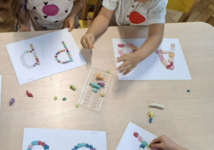 dzieci wyklejają litery plastelinowymi kropkami